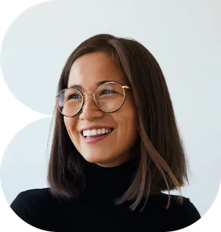 A woman with glasses wearing a black turtleneck sweater, smiling softly at the camera