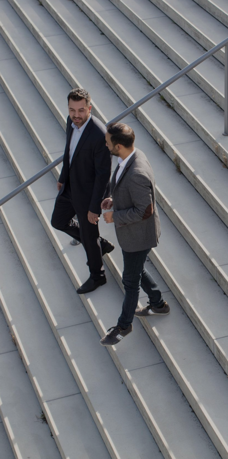  Two men in suits ascending a staircase, engaged in conversation as they move upward Two men in suits ascending a staircase, engaged in conversation as they move upward