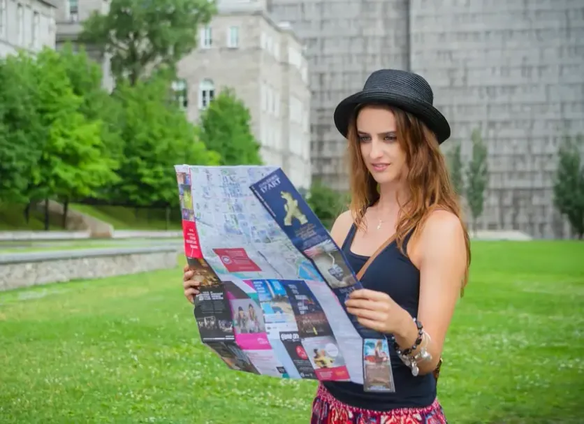 Woman wearing a hat and reading a map outdoors, representing travel and exploration.